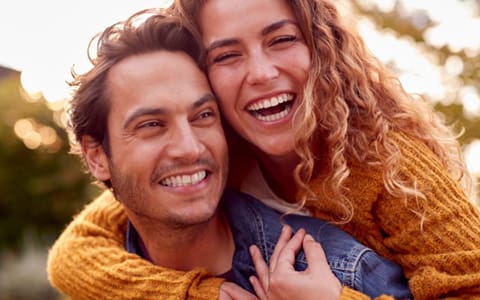 Portrait Of Happy Loving Couple With Man Giving Woman Piggyback